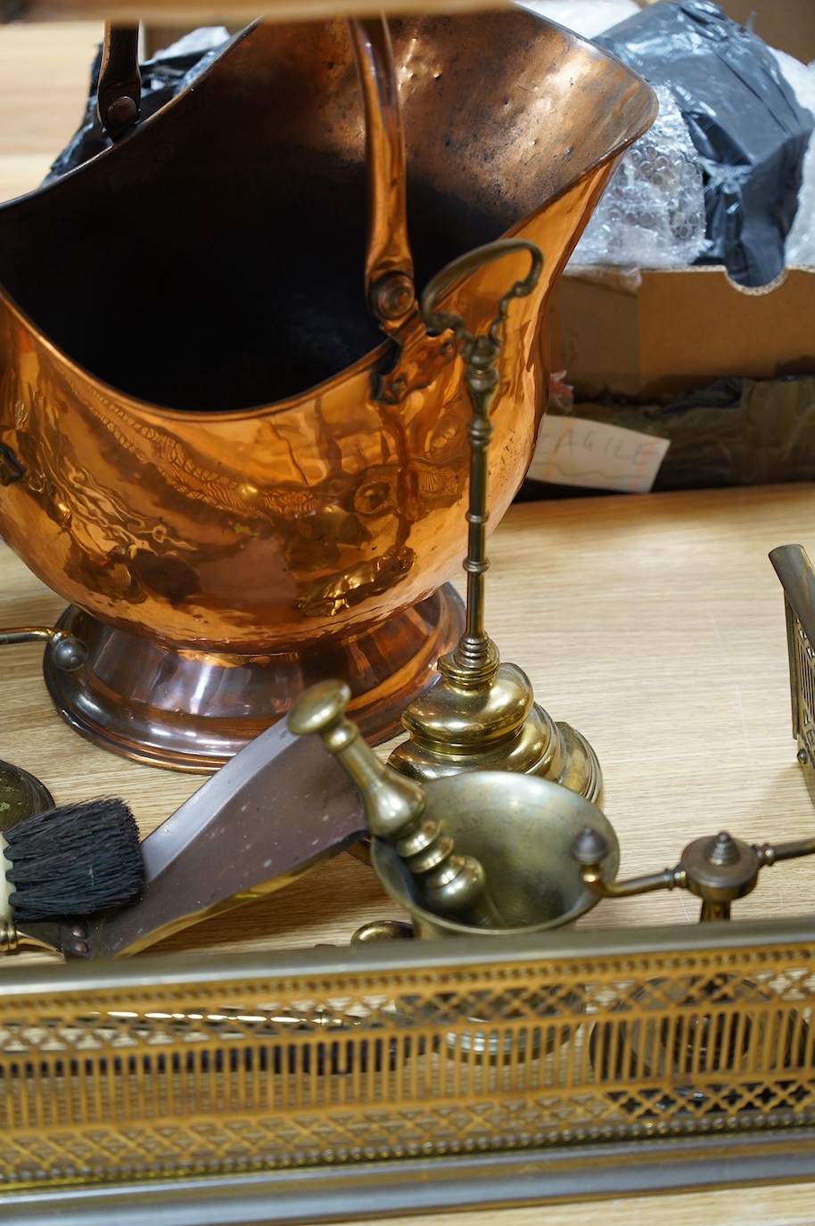 A Victorian brass fender, a fire screen, implements, fire dogs, a bronze pestle and mortar, a copper helmet coal scuttle, etc. Condition - fair